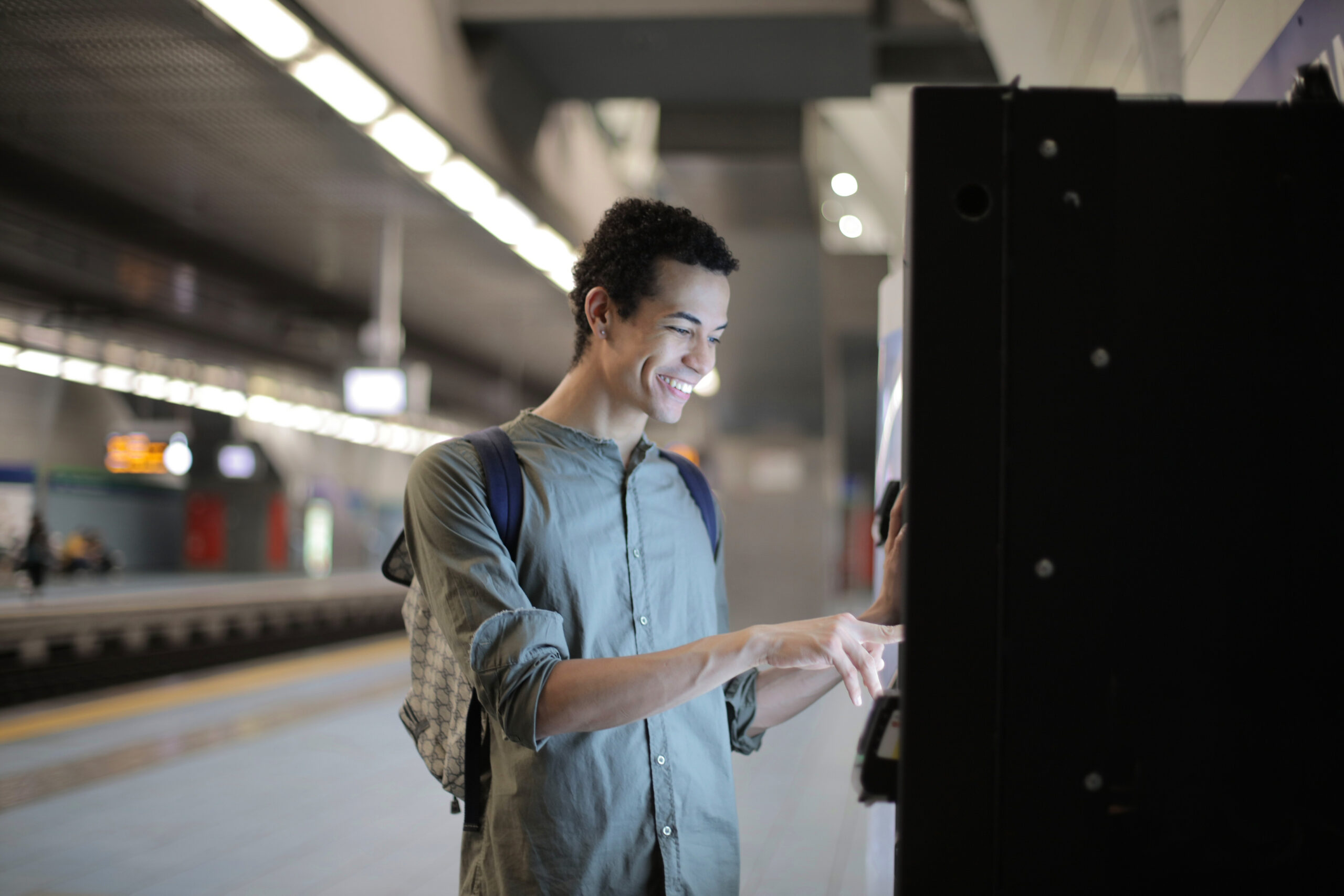 Canva – Cheerful ethnic man using ticketing machine at subway station